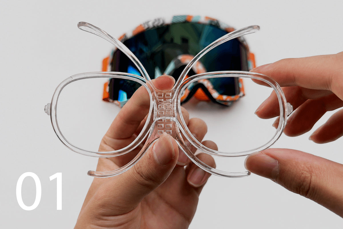 Hands adjusting the clear prescription goggle insert before installation.
