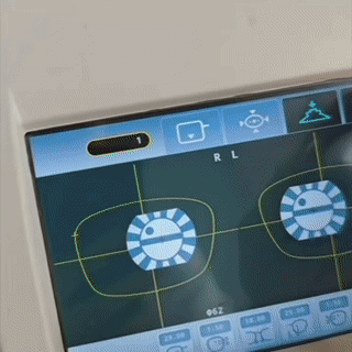 Prescription lens calibration screen showing left and right alignment targets during lens production. The display shows “R L” above the lens guides.